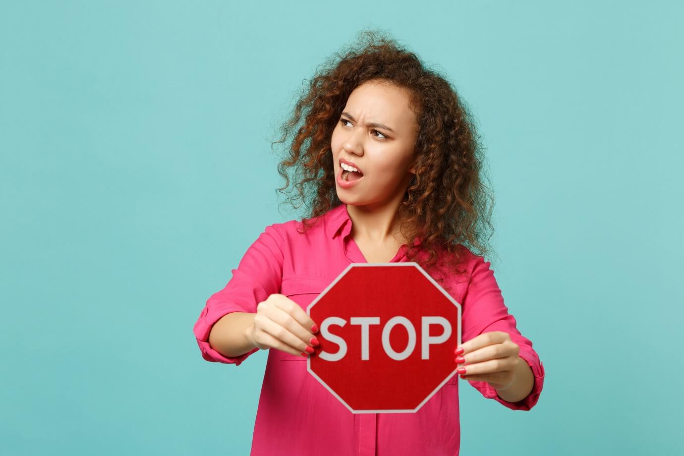 Woman holding a stop sign for the post stop feeling overwhelmed in business