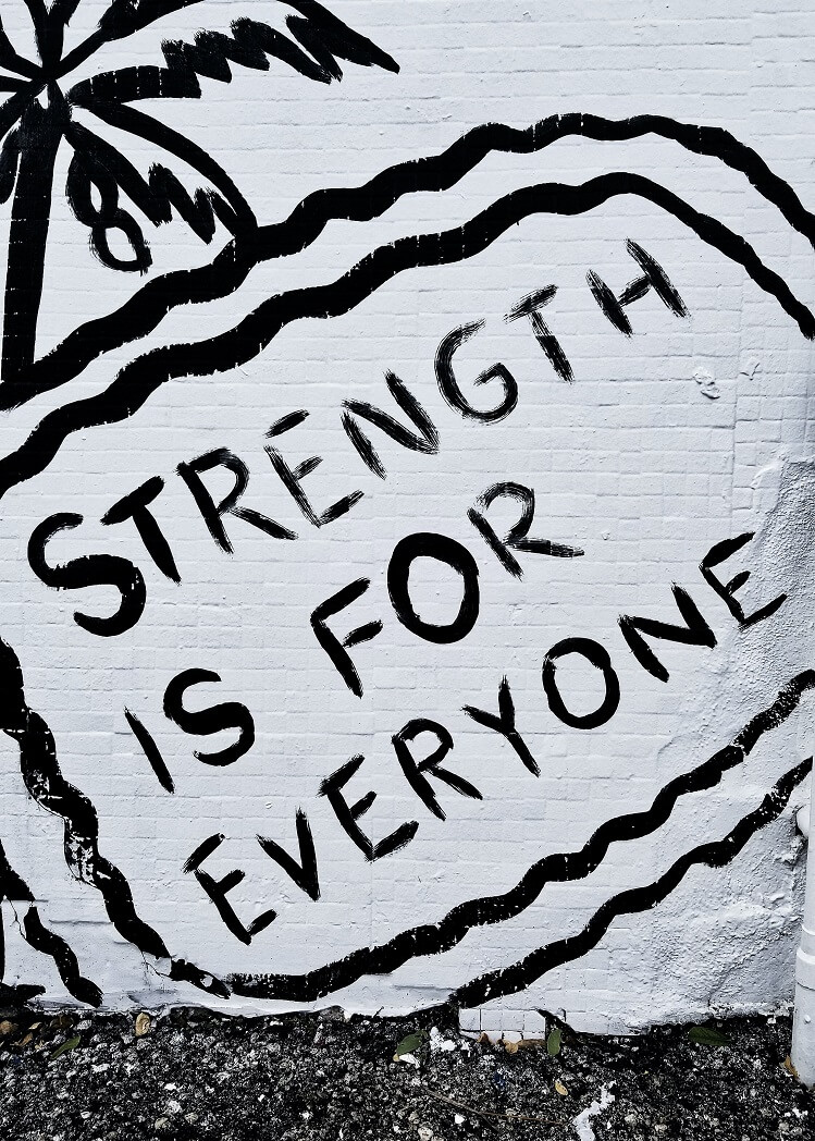 graffiti on wall that says strength is for everyone