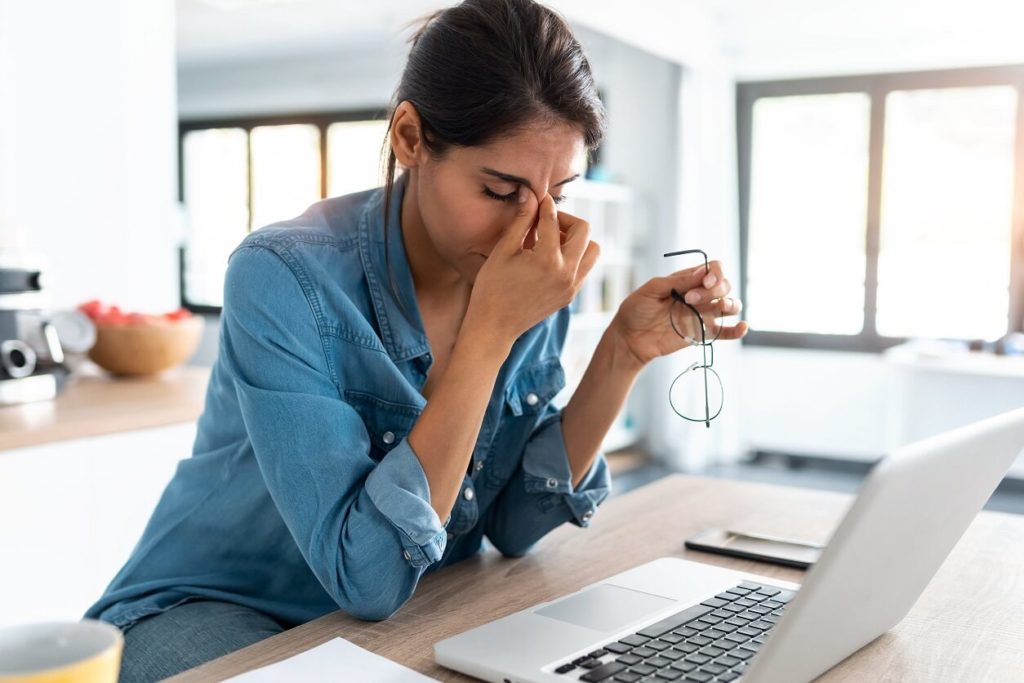 woman at computer with headache to show the frustrations one can experience when making Your Entrepreneurial Dream a Reality