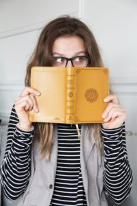 Woman peaking over a Bible