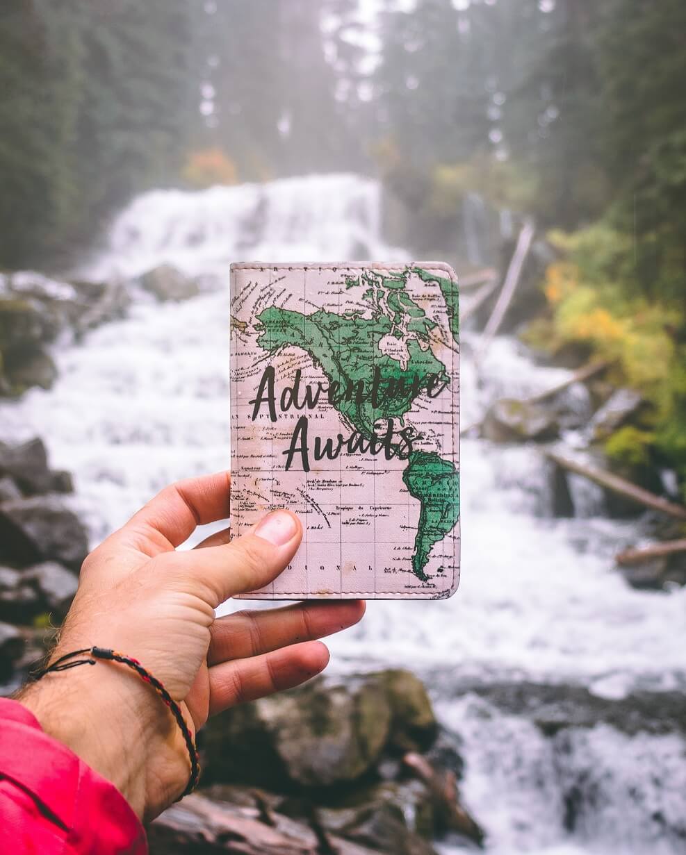 Woman holding a journal with adventure awaits on the cover.