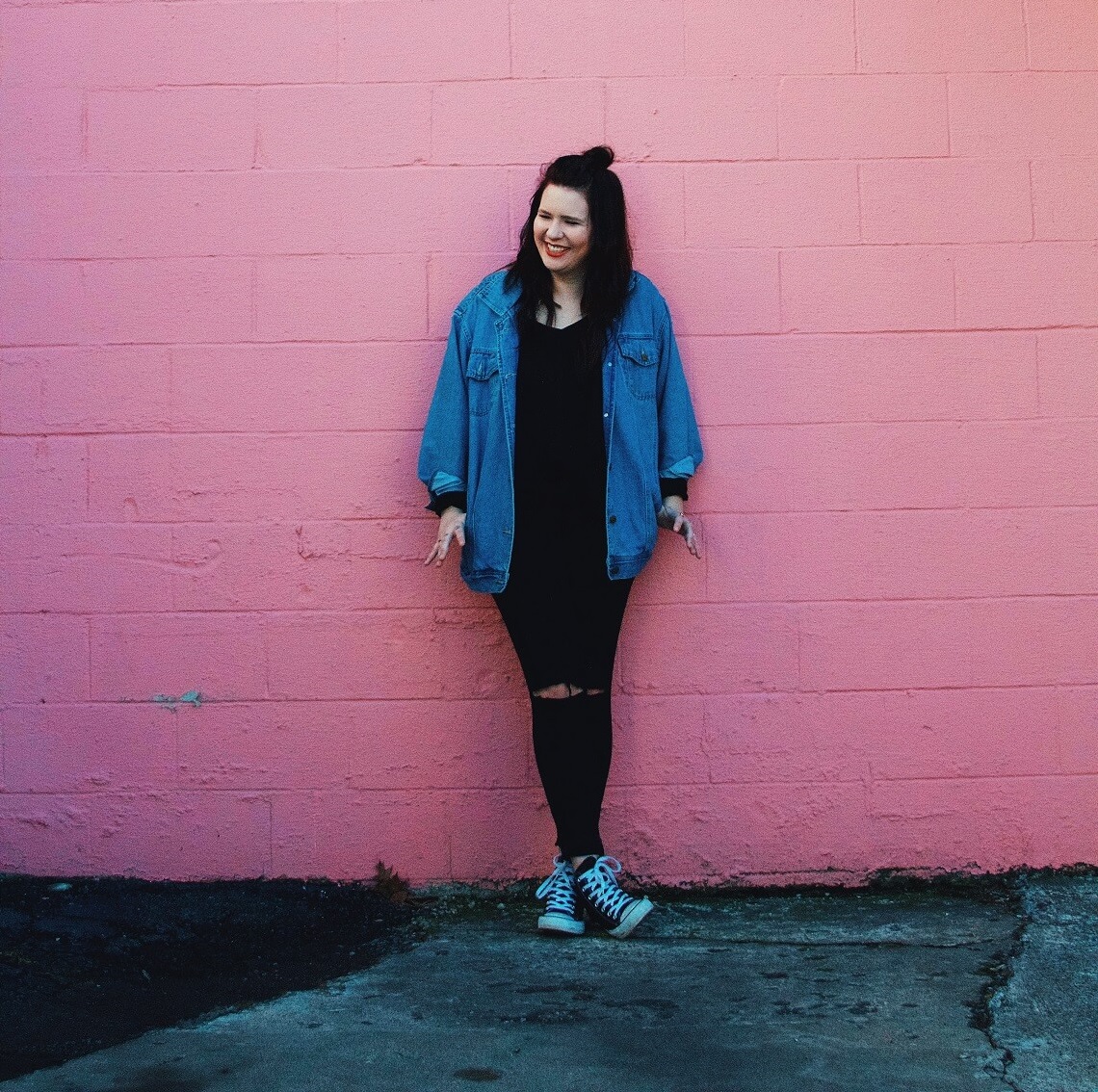 Lean Into God to Step Into Your Calling woman leaning on pink wall smiling