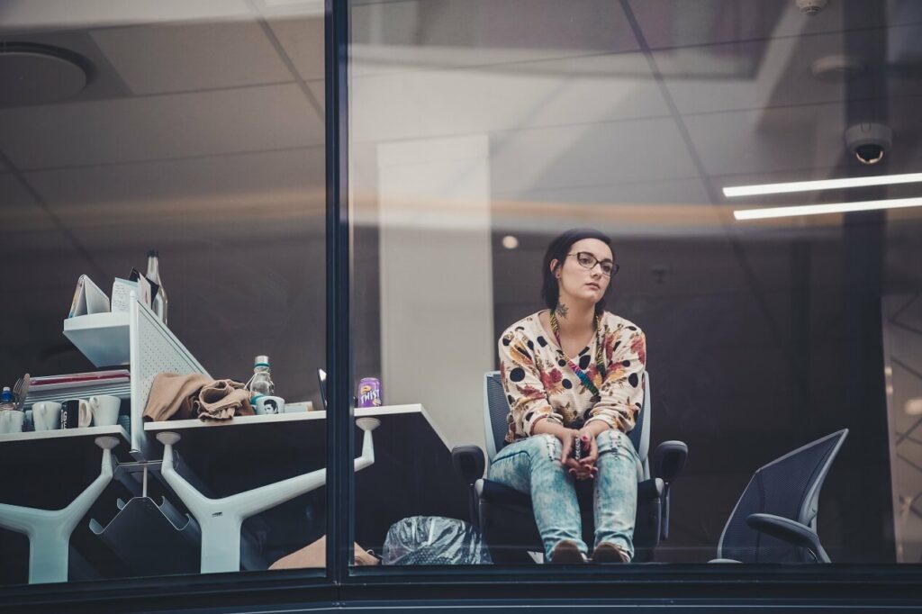 a woman looking out of her office building window to demonstrate how to get unstuck in your business because she looks stuck in her office for blog post how to Find meaning in your work by transitioning to what God is calling you to do