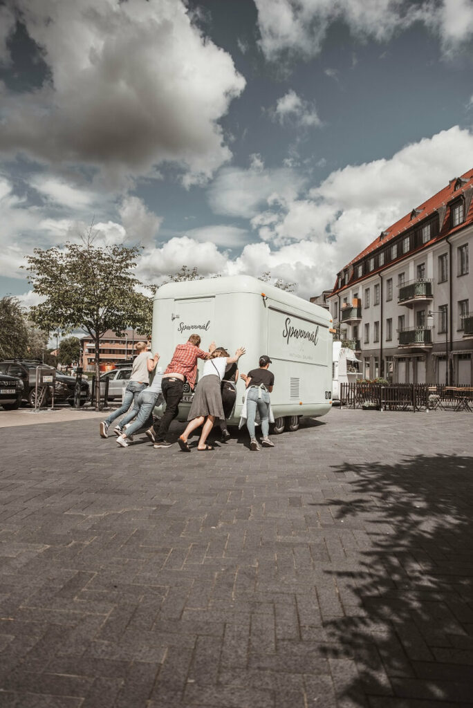 group of people pushing a food truck to show how to get unstuck in your business with the help of others