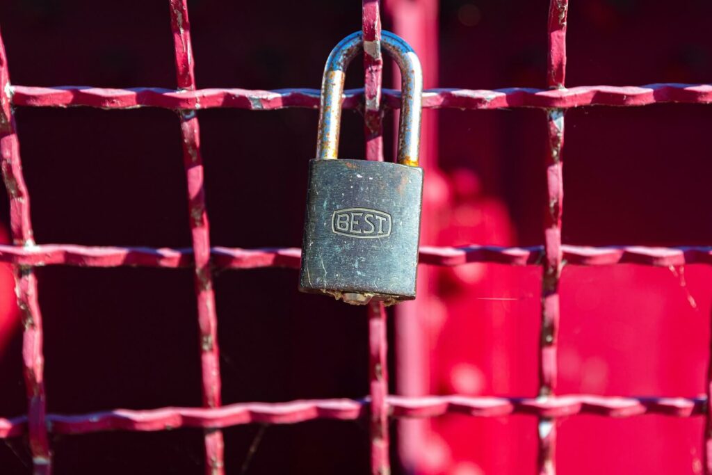 Image of a lock on a pink fence with word BEST engraved on lock.