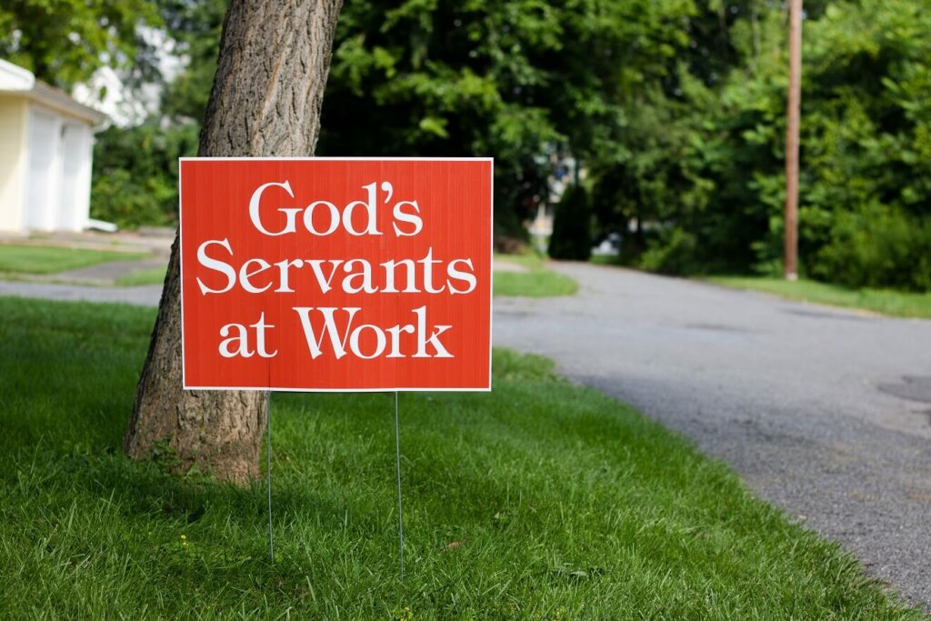Sign in grass that says God's servants at work