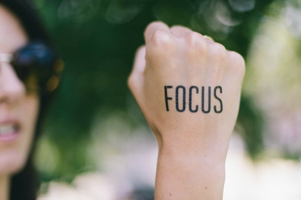 Image of a woman holding up her fist with the word FOCUS written on back of hand.