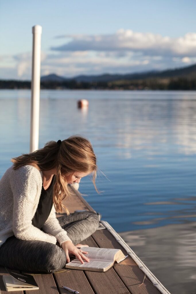 A woman reading the Bible on a dock
