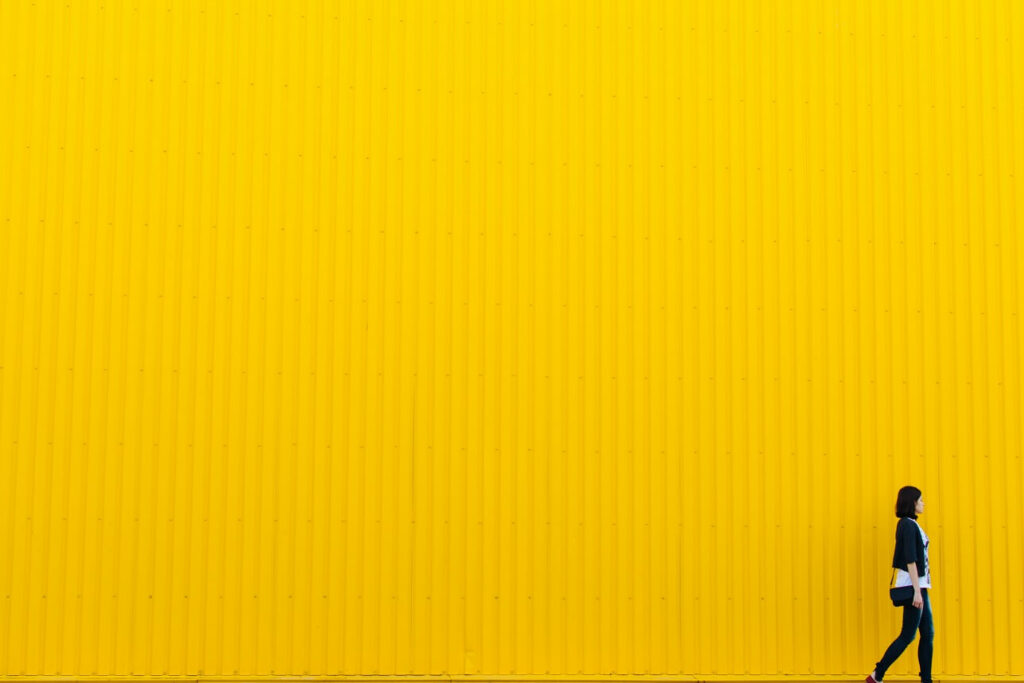 woman walking in front of a simple blank yellow wall for blog post on a simple business plan