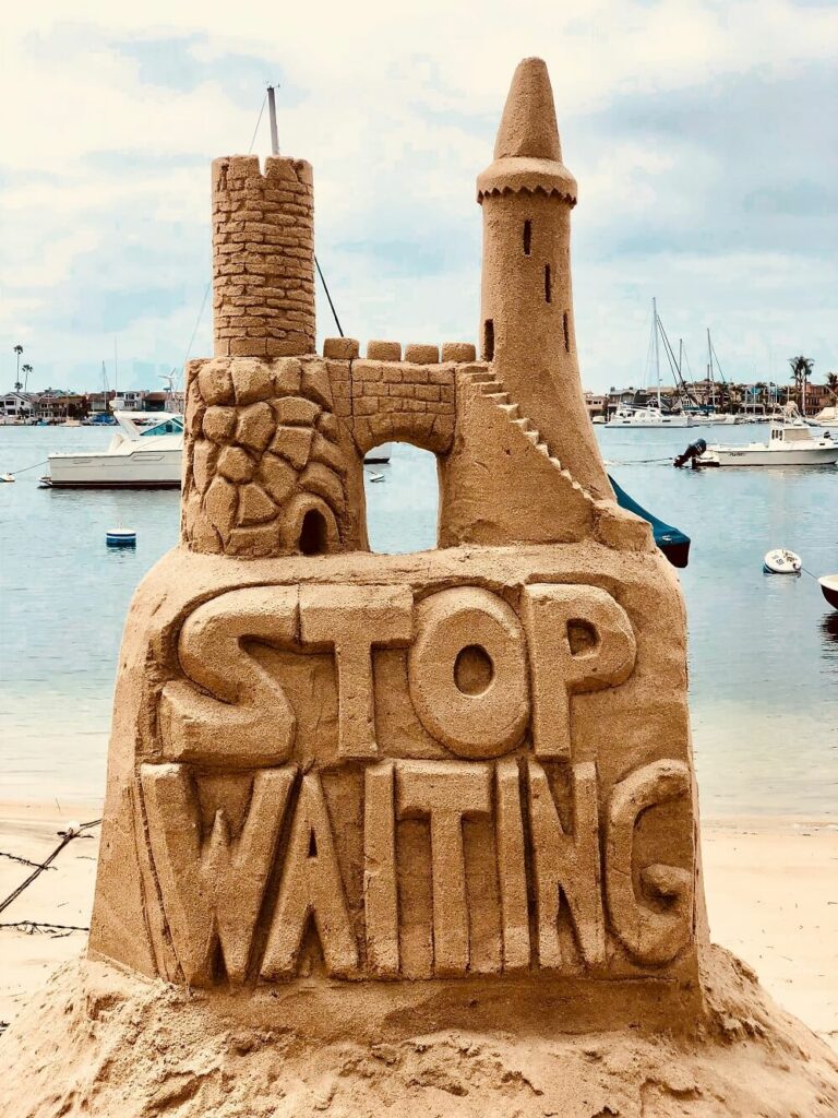 Sand castle that says stop waiting